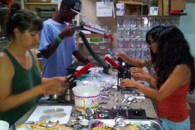 Three volunteers from Derechos Humanos work with Cedric of the Gloo Factory to make a few hundred buttons. 